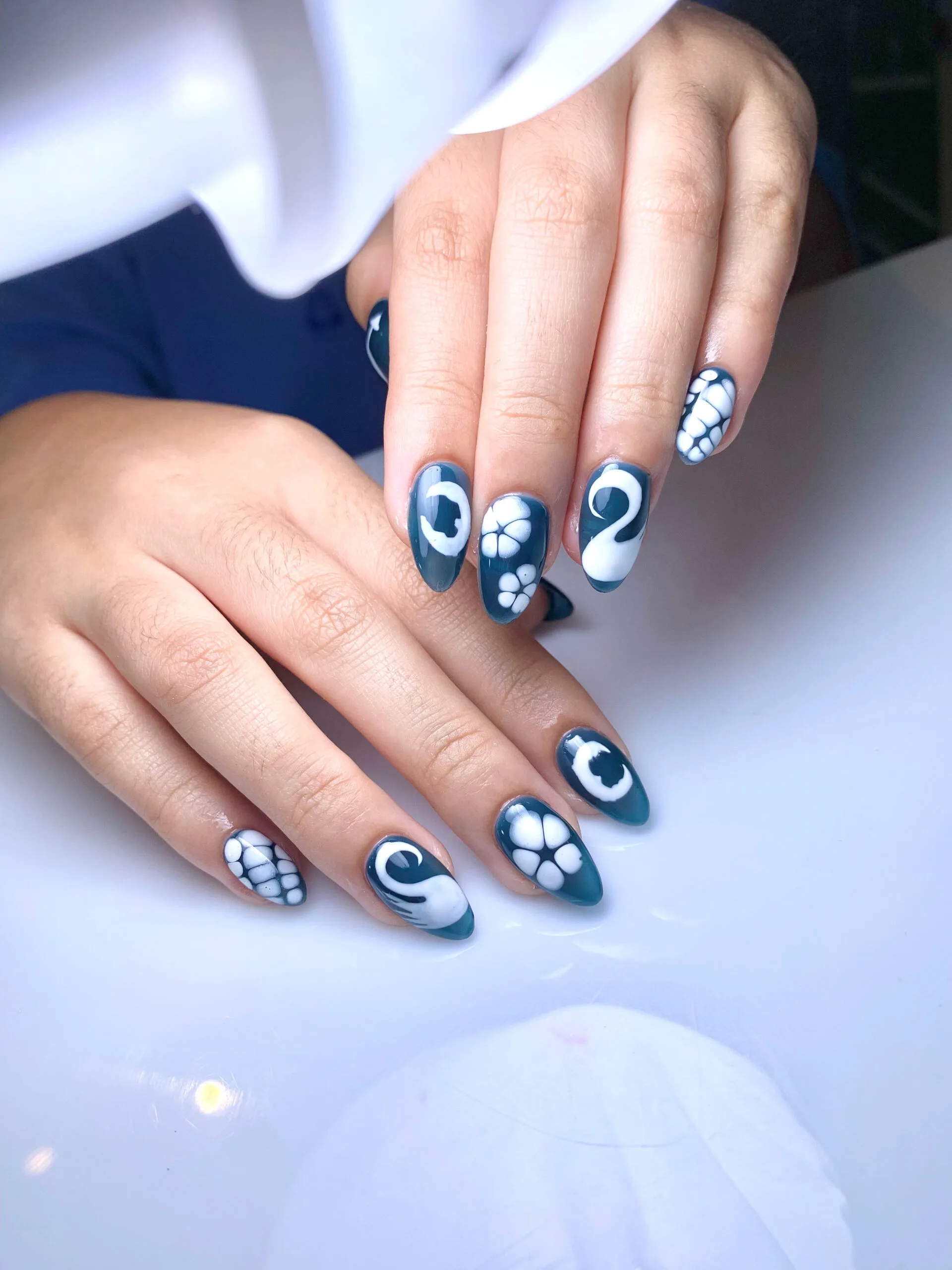 Nail art biru dengan motif bunga putih
