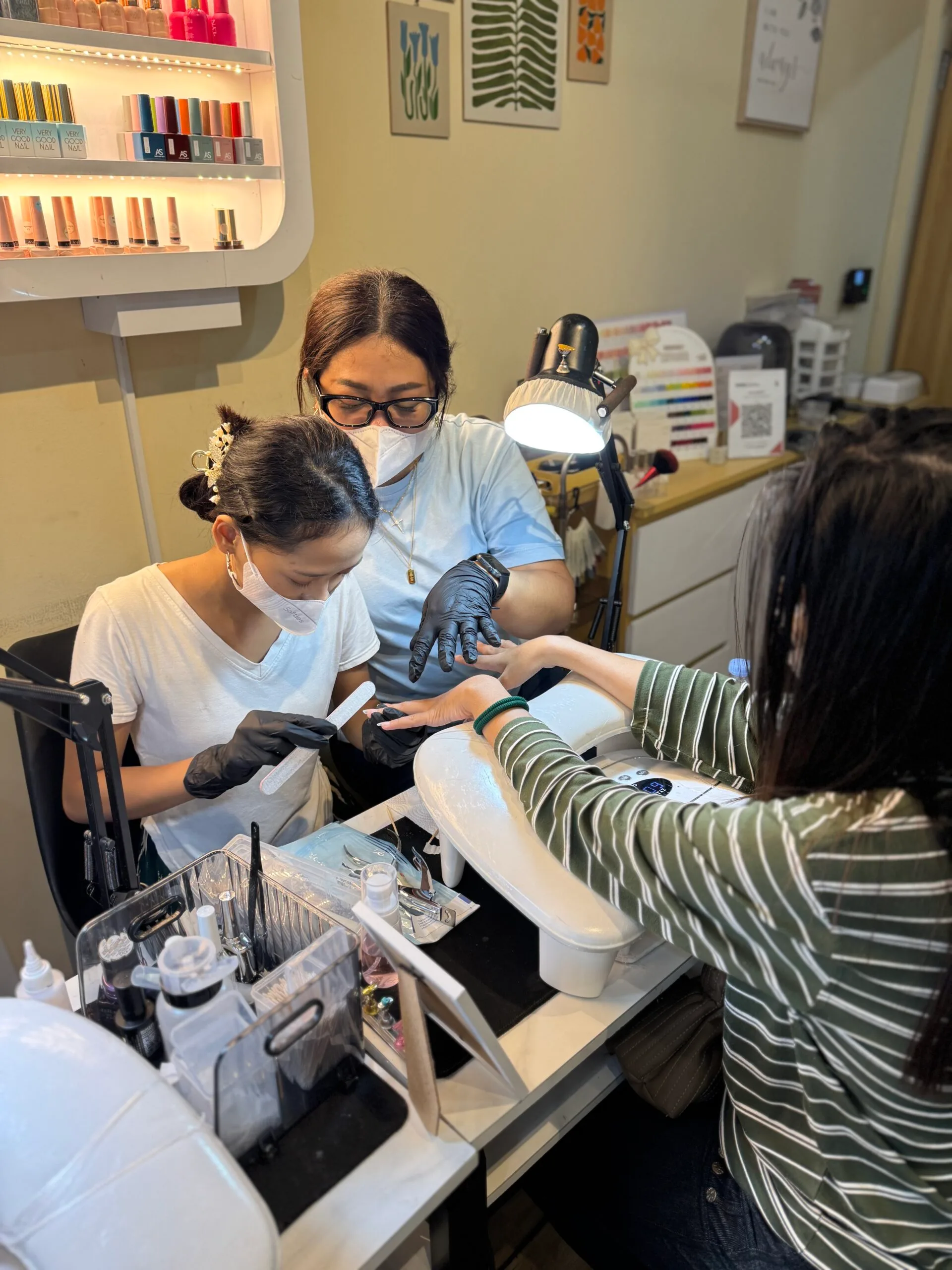 Dua murid praktik manicure dengan mesin e-file saat kursus