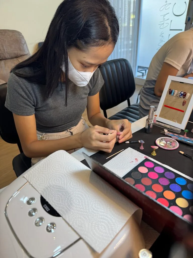 Murid memilih warna dari palet saat kursus nail art