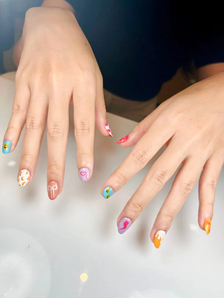 Nail art warna-warni dengan desain berbeda di tiap kuku