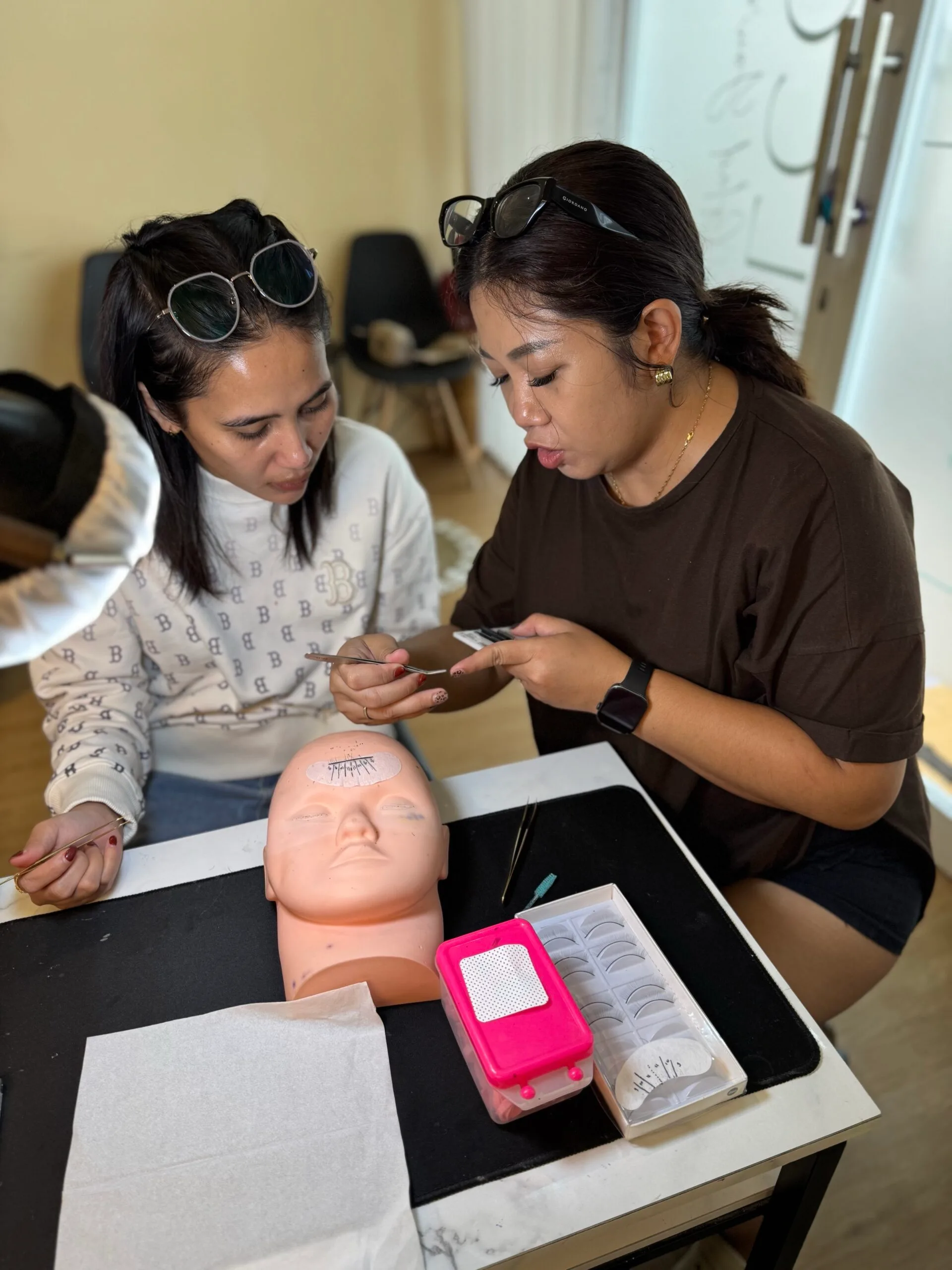 Dua murid berlatih eyelash extension pada mannequin