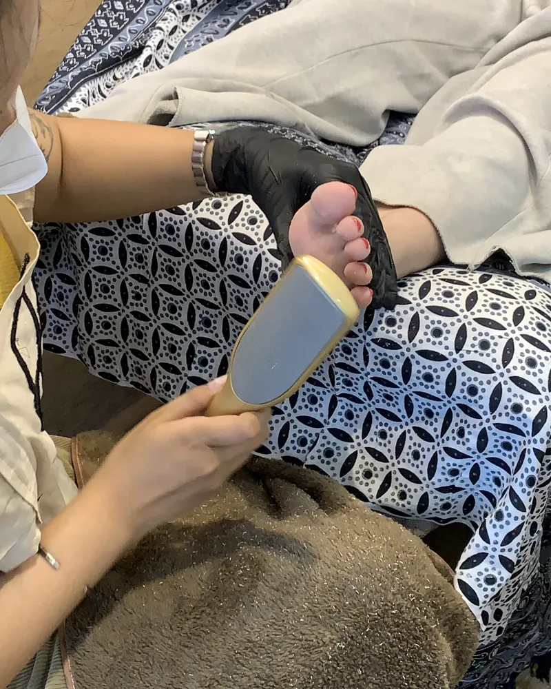 Beautician menghaluskan telapak kaki dengan foot file di Feta Beauty
